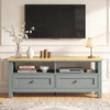 [Grey] Oskara TV unit front view in living room below wall-mounted TV styled with blossom vase, white ribbed vase, gold candles, and table lamp