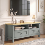 [Grey] Oskara TV unit in a living room below wall-mounted TV with open shelves holding books and media player styled with blossom vase and lamp
