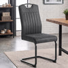 [Grey] Industrial style dining chair by a wood table with upholstery, carry grip and black loop metal frame.