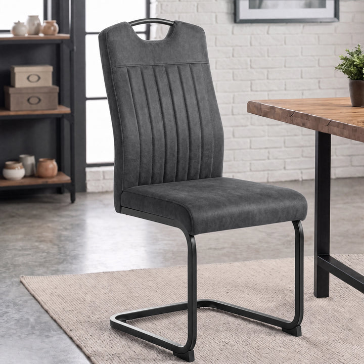 [Grey] Industrial style dining chair by a wood table with upholstery, carry grip and black loop metal frame.