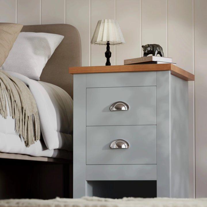 [Grey] angled view of grey shaker nightstand with cup handles oak effect top lamp and ornament on top