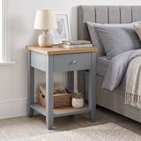 [Grey] Angled view of Grey Shaker Bedside Table with natural oak top, drawer, and open shelf styled by bed.
