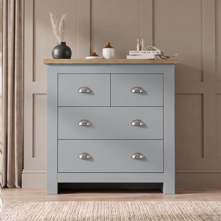 [Grey] Four drawer chest front view with oak top, chrome cup handles, pampas vase, books, and panelled wall