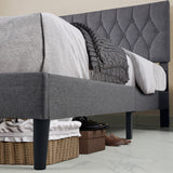 Grey single bed frame with tufted linen headboard and under-bed storage space with shoes.