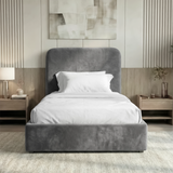 Front view of grey velvet single ottoman bed positioned between bedside tables in a bright interior and styled room