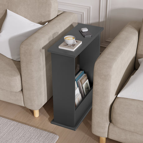Black side table with a cup of coffee and books between two beige armchairs.