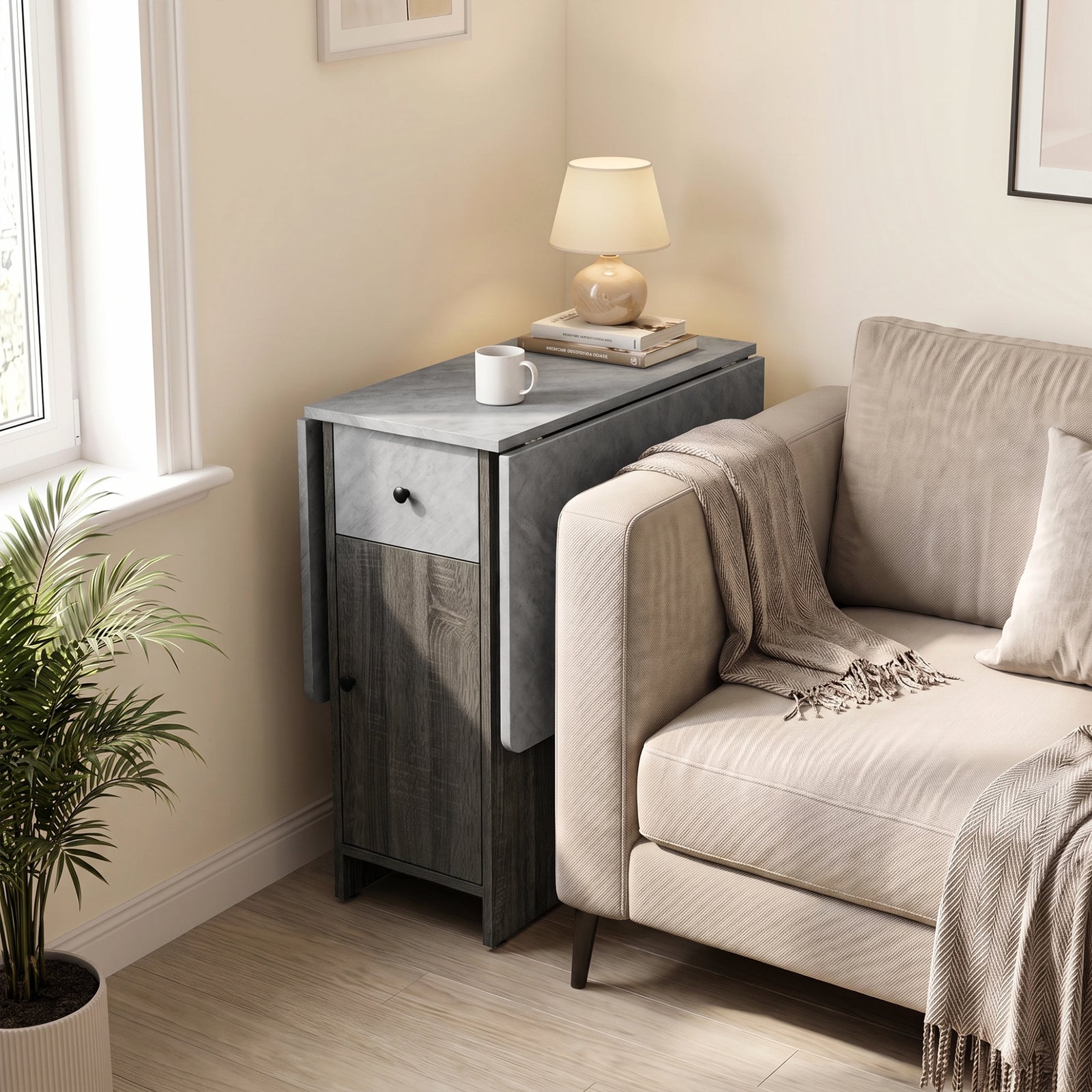 [Grey] Small folding dining table closed beside a sofa and window featuring a marble-effect top with lamp, books and a mug.