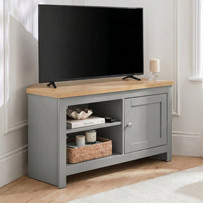 [Grey] Tavero Grey Corner TV Unit with Storage three-quarter view against white panelled wall showing oak top, open shelving with wicker basket and shaker doo