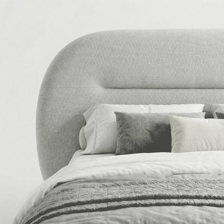 Close-up view of the padded headboard on the grey upholstered bed frame with light bedding