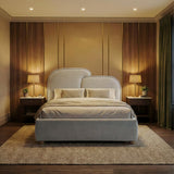 Grey double bed with divided cushioned headboard panels and softly textured upholstery in a warm lighting