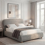 Grey fabric double bed shown in a bright bedroom, styled with layered bedding and soft lighting from a nearby window