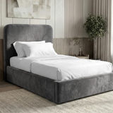 Grey velvet single ottoman storage bed viewed in a neutral interior with an upholstered frame and a padded headboard