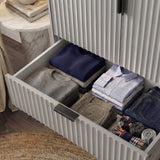 Grey wardrobe drawer storage section with organised folded garments inside and black metal sleek handles