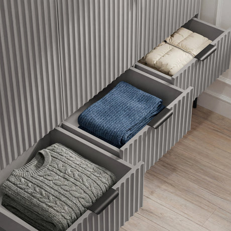 Grey wardrobe, lower three drawer unit partially open, displaying storage capacity and folded clothes neatly