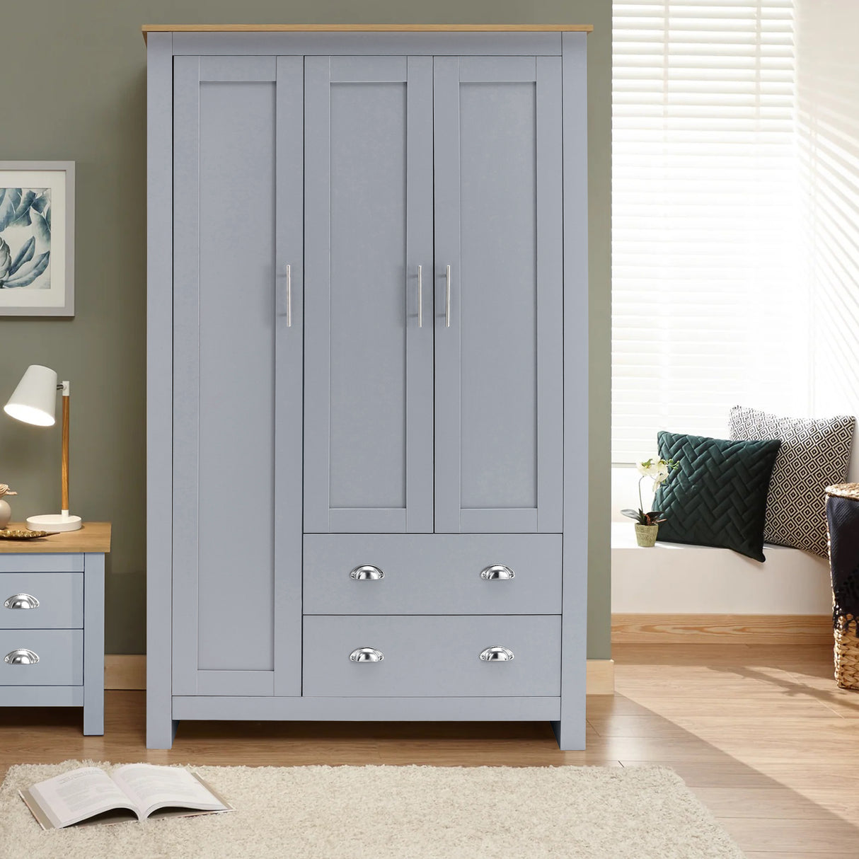 The grey wardrobe has three doors and drawers, and it has a modern design with silver handles.