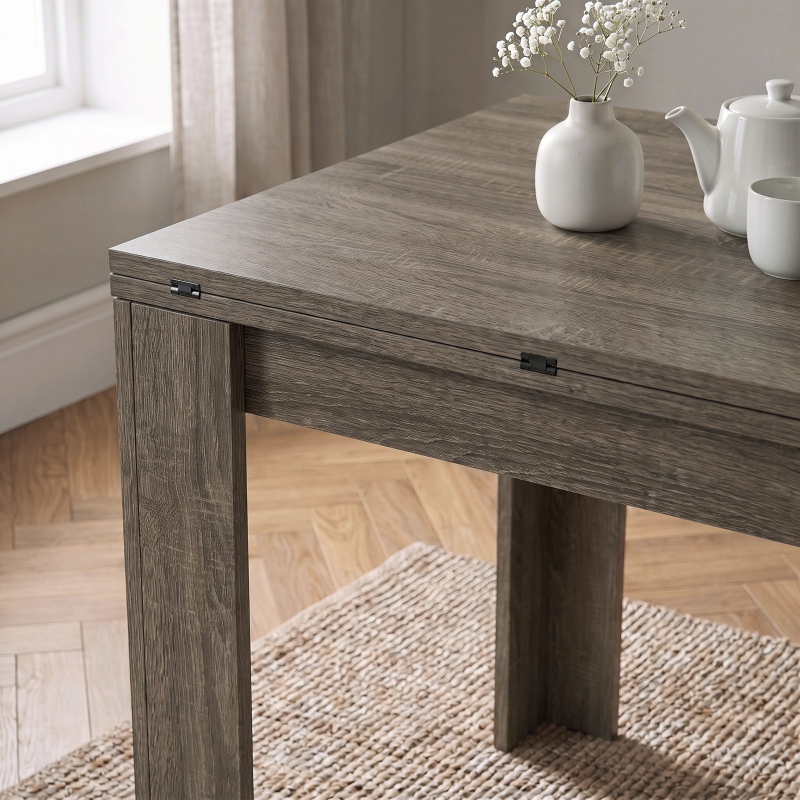 [Grey Wood] Close-up of folded wood-grain tabletop above apron and wide legs, with steel hinges, flower vase, teapot and cup