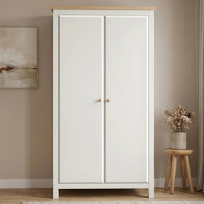 [White] wardrobe with wooden top in a room with a stool and plant