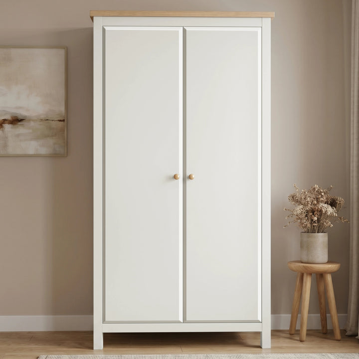 [White] wardrobe with wooden top in a room with a stool and plant