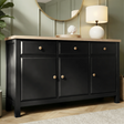[Black] Haven 3-door sideboard in a styled bedroom corner with round mirror and table lamp on oak veneer top