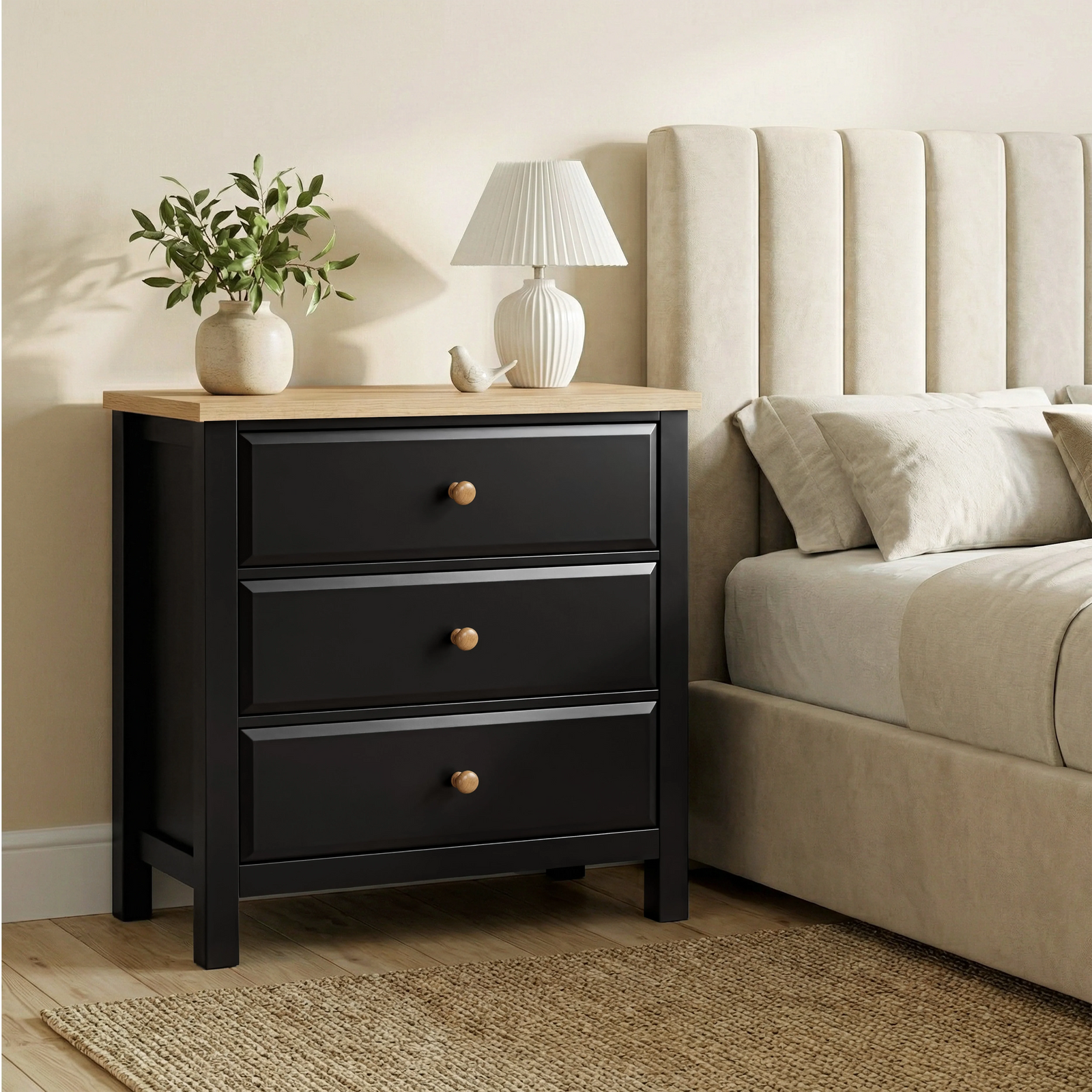 [Black] Haven 3-drawer chest beside upholstered bed headboard with lit pleated lamp on oak top