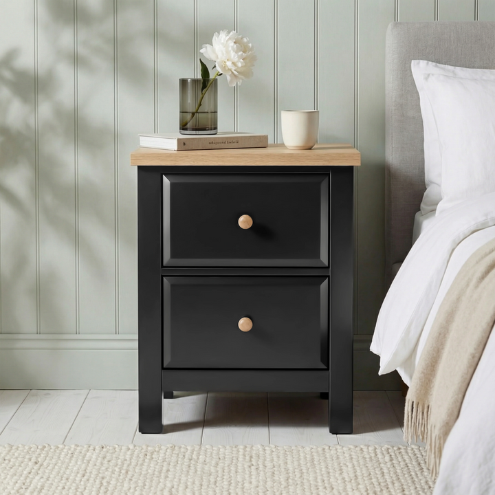 [Black] Haven 2-drawer bedside table front view in a styled bedroom setting with lamp and accessories on top