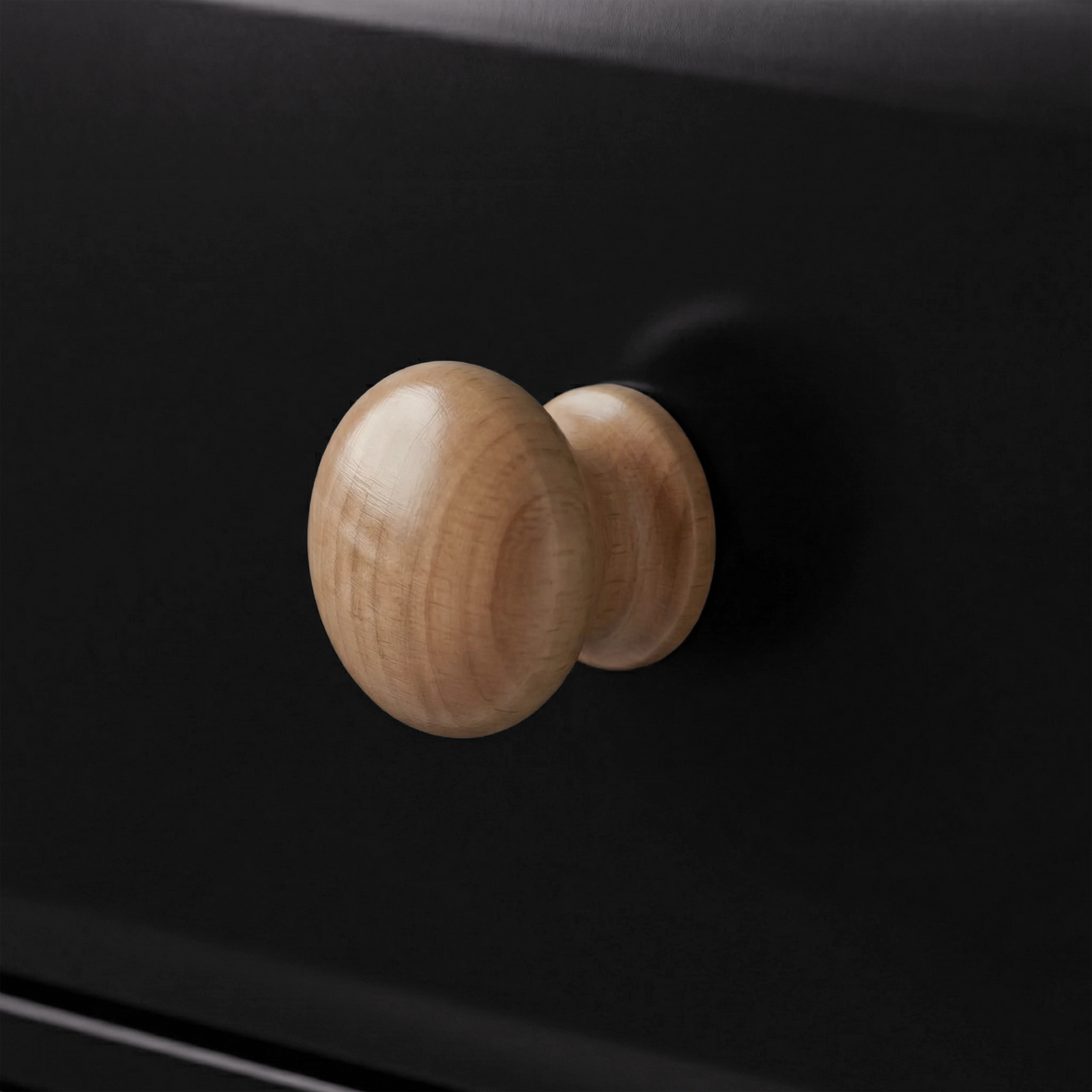 [Black] Close-up of a single round natural wood knob on a black painted drawer front of Haven chest of drawers