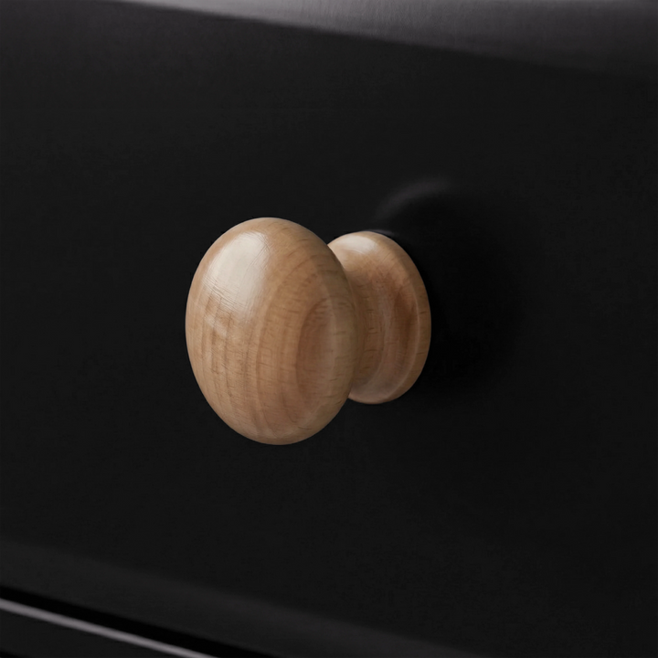 [Black] Close-up of a single round natural wood knob on a black painted drawer front of Haven chest of drawers
