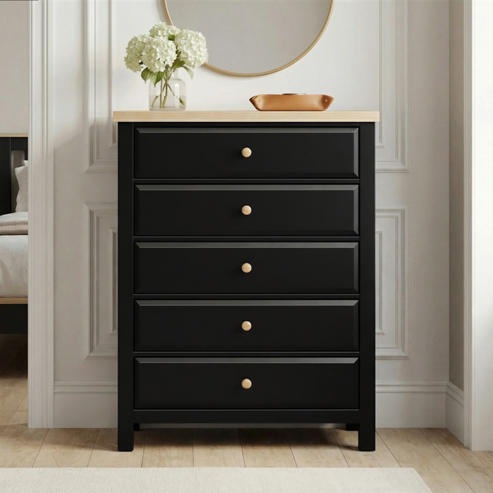 [Black] Haven 5-drawer tall chest front view in a styled room with round mirror and flower arrangement on oak top