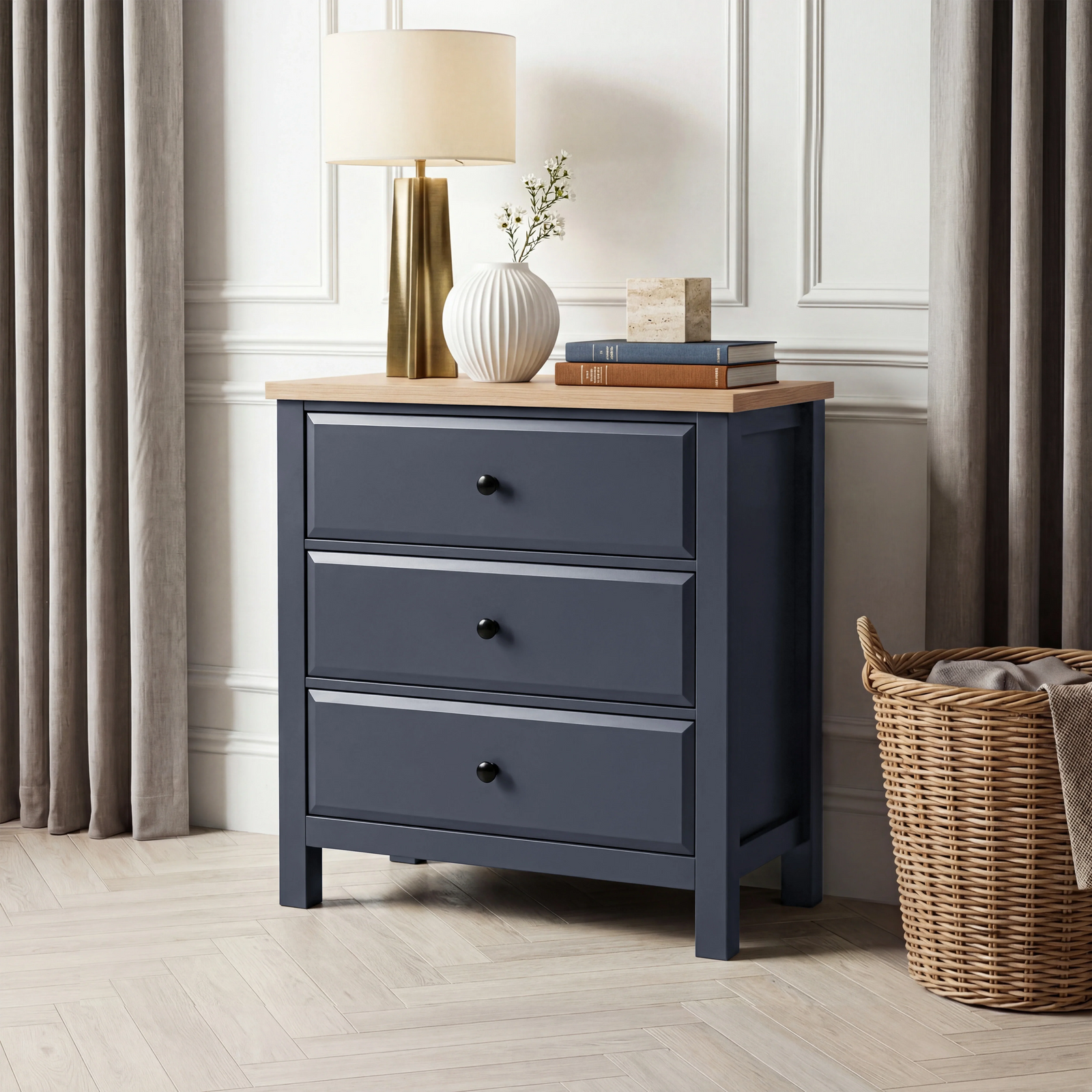 [Blue] Haven 3-drawer chest in panelled room with lamp, vase and books on oak top and woven basket on floor right