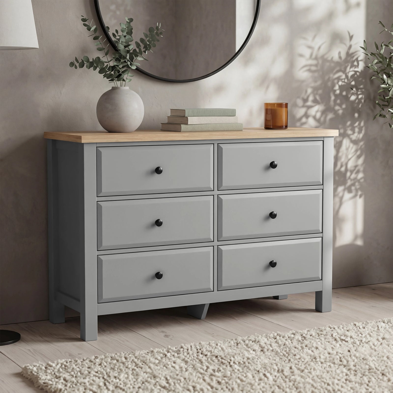 [Grey] Haven 6-drawer chest in a bedroom setting with round mirror, plant and candle on the oak top surface