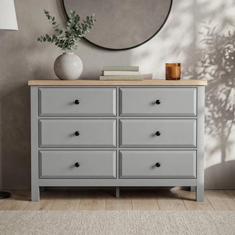 [Grey] Haven 6-drawer chest front view in a styled room with vase, candle and dried botanicals on oak top