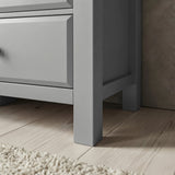 [Grey] Haven chest leg and floor clearance close-up on wide wood planks beside fringed cream rug edge