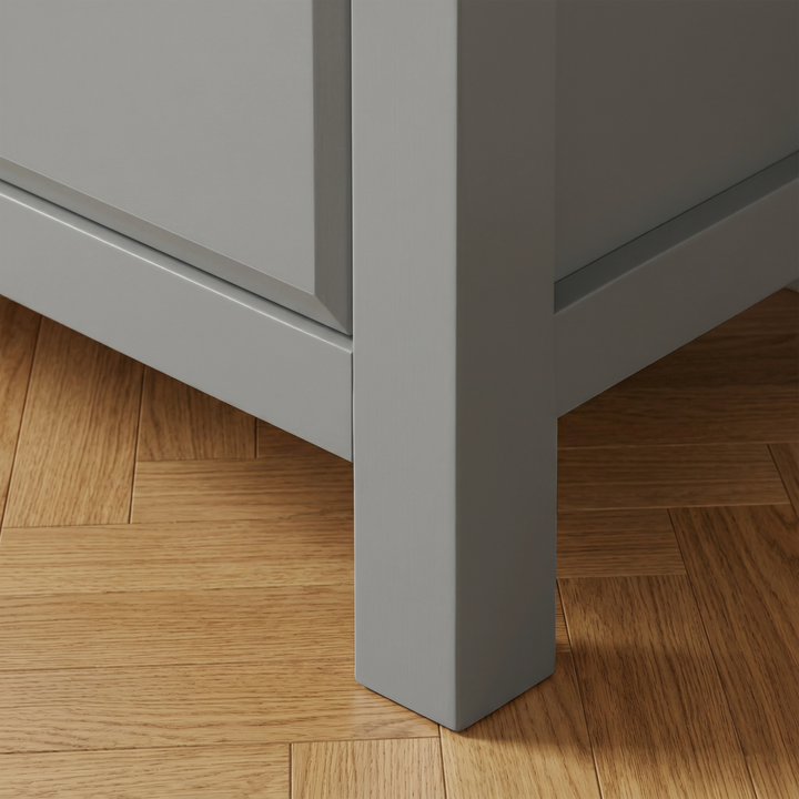 [Grey] Haven 5-drawer tall chest angled close-up showing painted frame leg and base detail against wooden floor