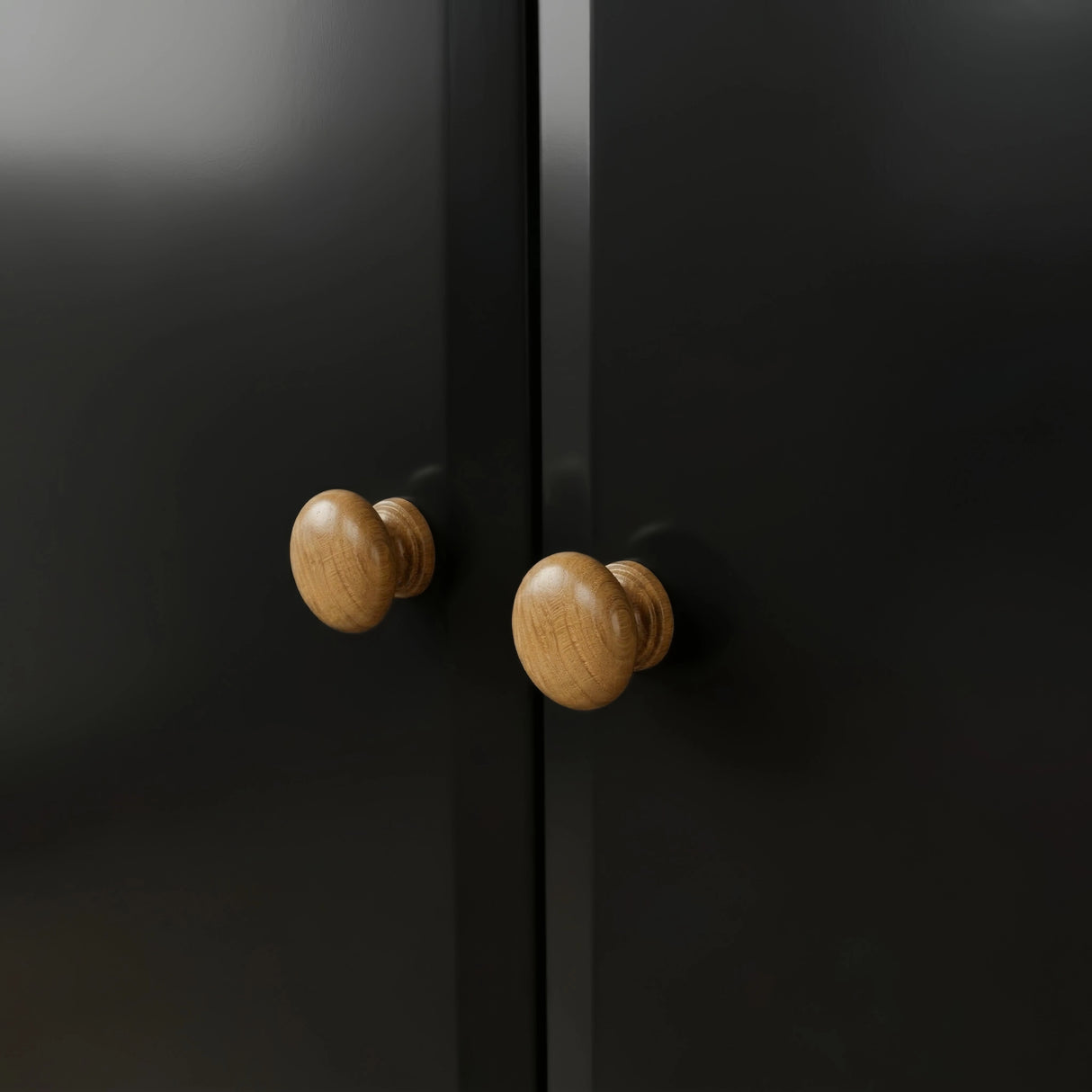[Black] Pair of round oak knobs on the Haven 2 door wardrobe where the two black doors meet.