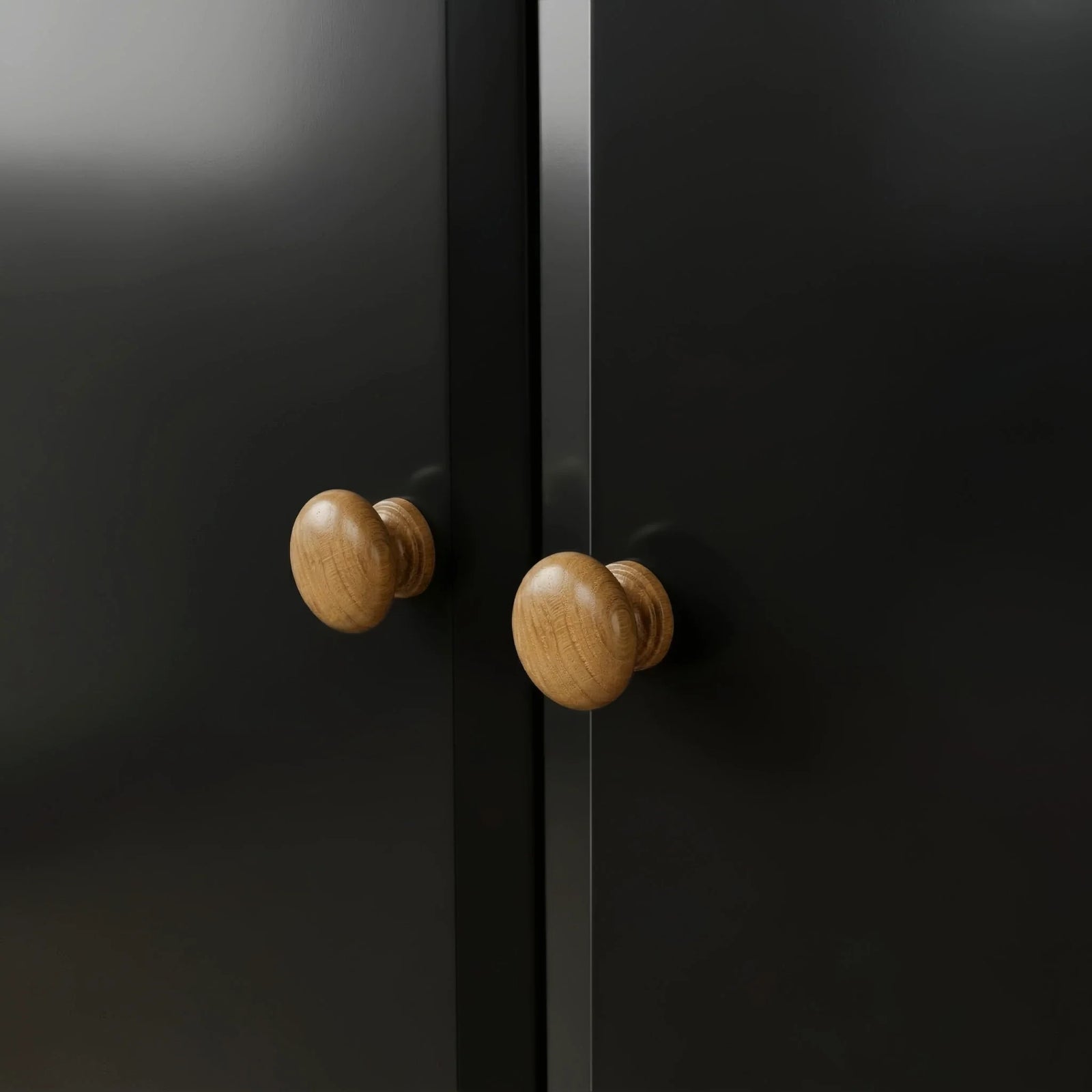 [Black] Pair of round oak knobs on the Haven 2 door wardrobe where the two black doors meet.