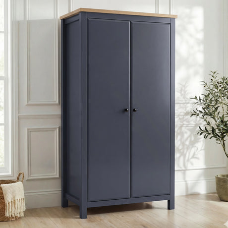 [Blue] Haven wardrobe angled in a bright room, blue painted 2 door frame with warm oak top and round black knobs