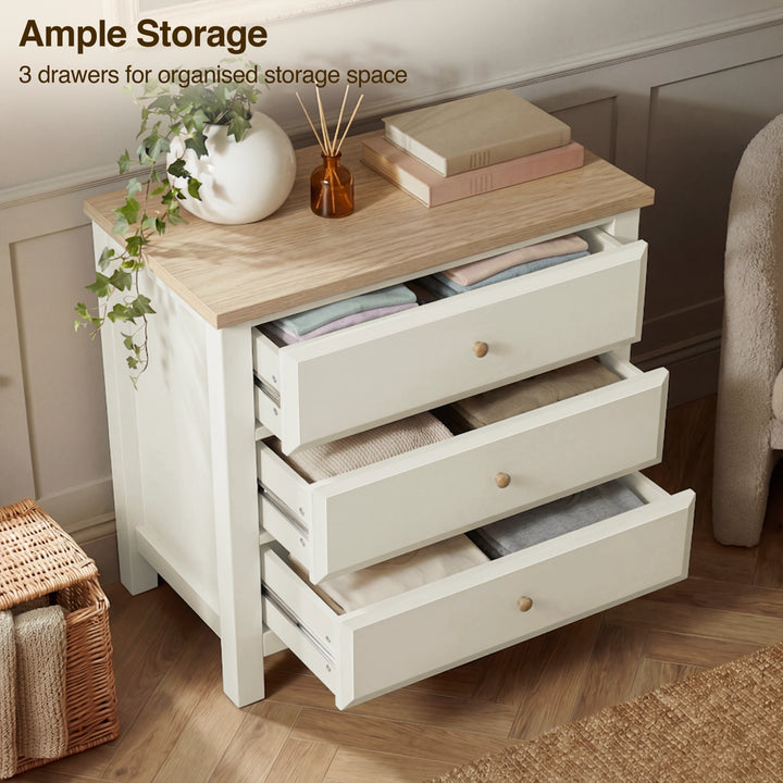 [White] dresser with three drawers on a wooden floor, featuring decorative items on top
