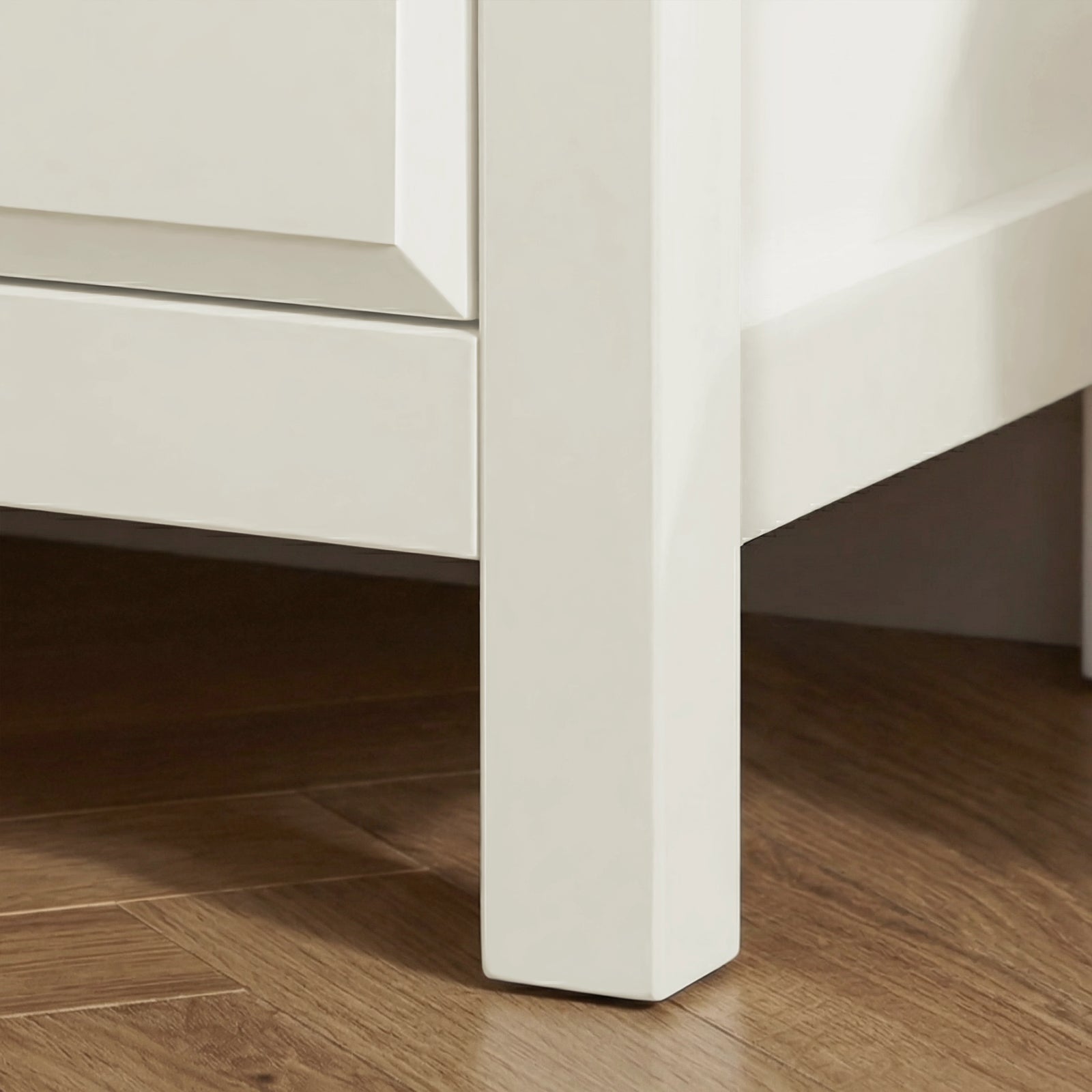 [White] Haven 3-drawer chest angled close-up showing painted frame leg detail and base against a wooden floor