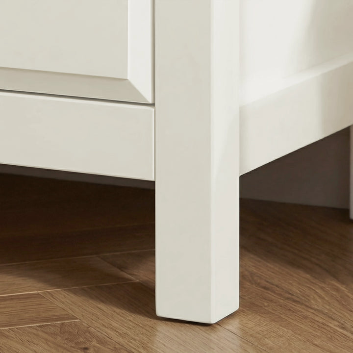 [White] Haven 3-drawer chest angled close-up showing painted frame leg detail and base against a wooden floor