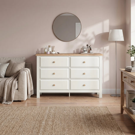 [White] dresser with wooden top in a bedroom setting with a mirror and lamp.