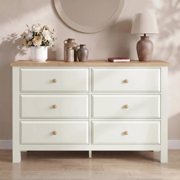 [White] dresser with wooden top against a neutral wall with decorative items
