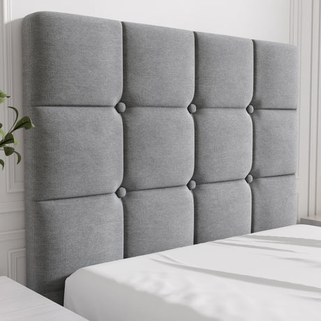 Gray tufted headboard on a bed with white bedding