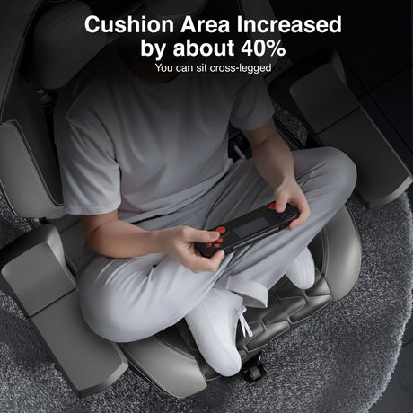 Person sitting on a massage chair with increased cushion area, holding a remote control.