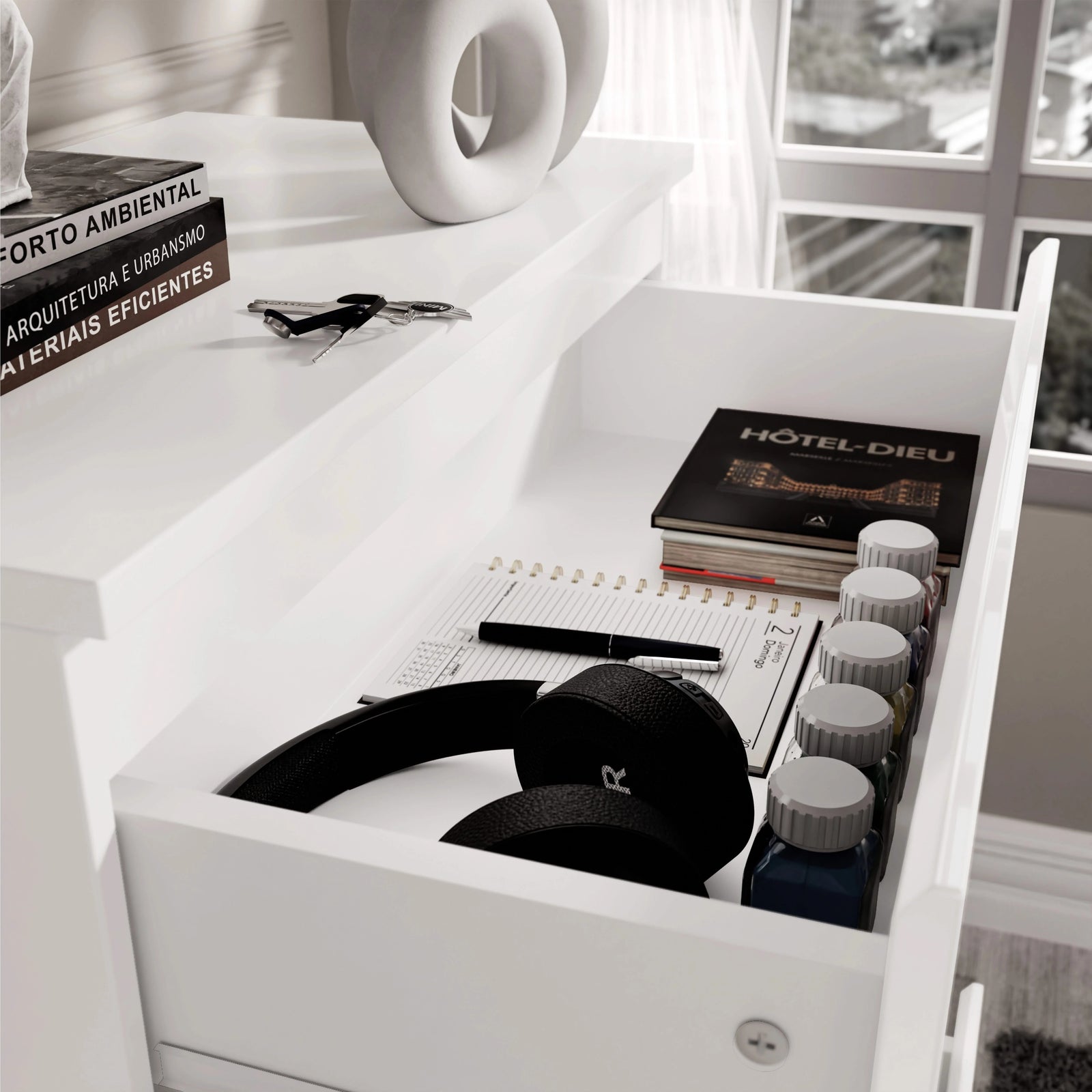 [White] White 4 Drawer Chest of Drawers top drawer interior, headphones beside hardback book labelled HOTEL-DIEU.