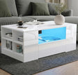 [White] high gloss white coffee table with blue LED middle recess, side cubbies and grey sectional sofa behind
