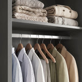 [High Gloss Grey] Torvek wardrobe interior close-up of chrome hanging rail with jackets and upper shelf with folded knits