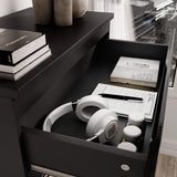 [Black] Open top drawer of black high gloss tall chest of drawers with white headphones and notebooks