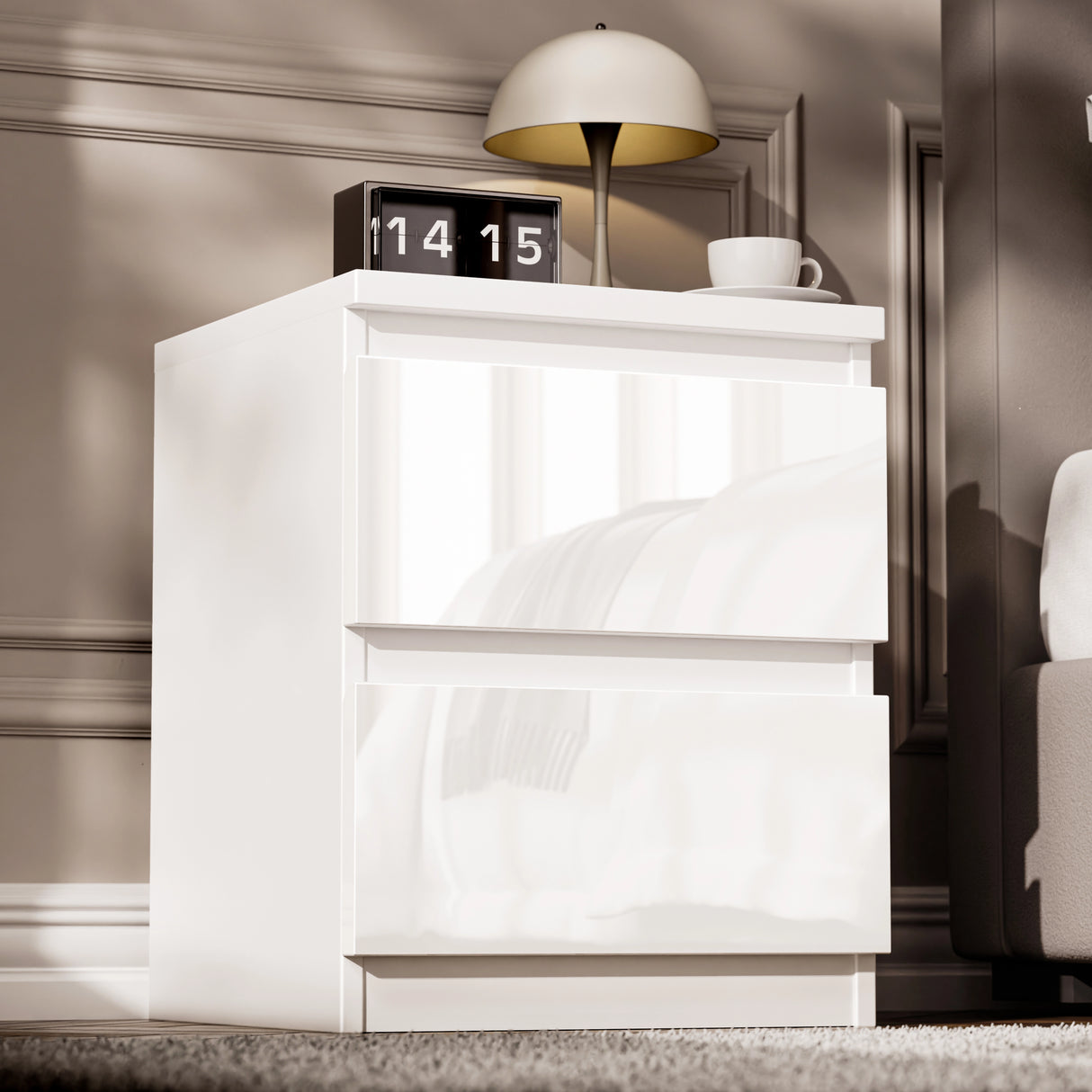 High Gloss 2 Drawer Bedside Table in white with modern design, placed beside a bed with a lamp, clock, and cup on top. Ideal for bedroom storage.