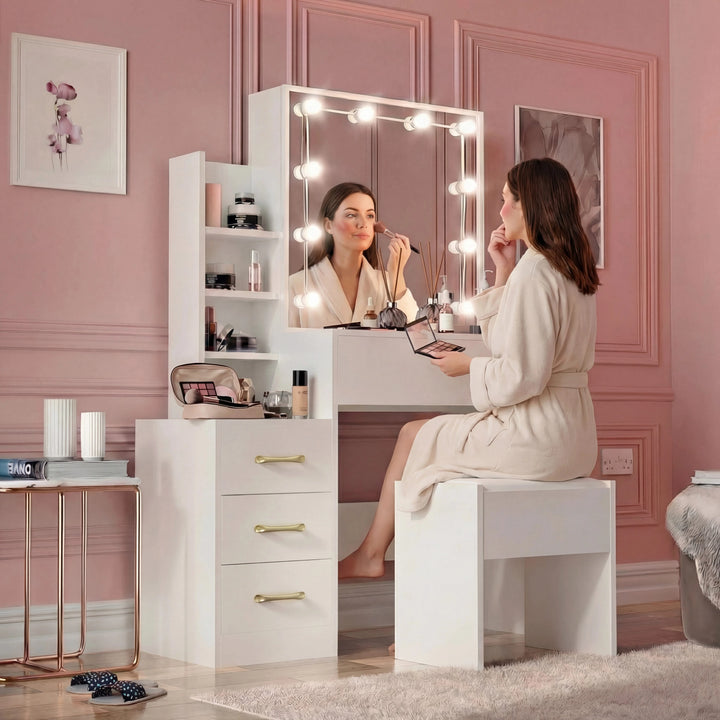 [White] In-use shot of white Hollywood mirror dressing table, drawers closed with gold handles, stool occupied