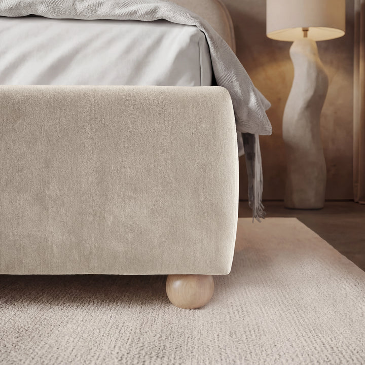 [King | Beige] Corner side detail of beige king bed frame emphasizing soft fabric texture of footboard and wooden legs